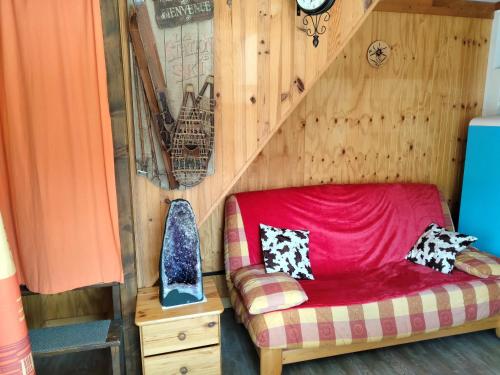 Sofá rojo en una habitación con pared de madera en Chalet à proximité de l'Ubaye en Jausiers