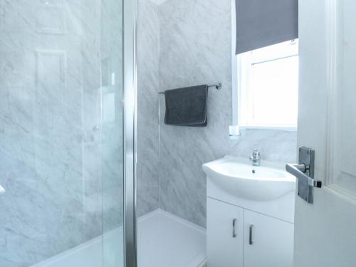 a white bathroom with a shower and a sink at California Summers in Great Yarmouth