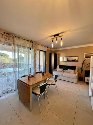 un salon avec une table et des chaises et un lit dans l'établissement le verger des naiades, au Lavandou