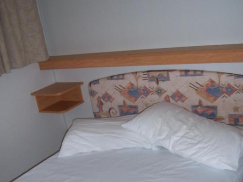 a bed with a white pillow and a wooden headboard at Le sorgenti - Mobile Home 55 in Palazzuolo sul Senio