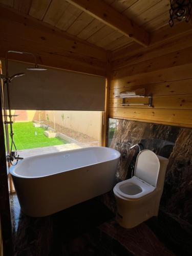 ein Bad mit einer Badewanne und einem WC in der Unterkunft منتجع اكواخ كيفا in Tabuk