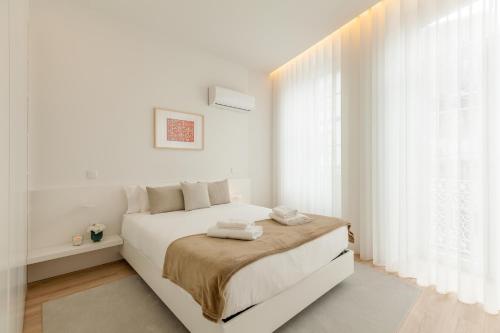 a white bedroom with a bed with towels on it at Boavista Collection Ap for Family by Sé Apartamentos in Braga