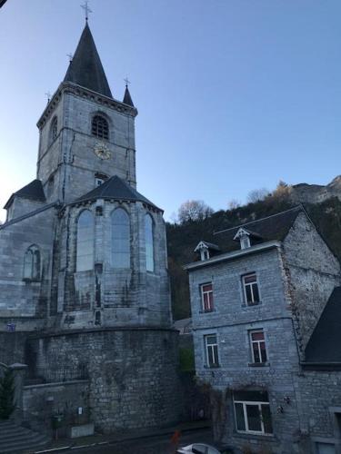 an old church with a clock tower next to a building at Les colombages in Dinant