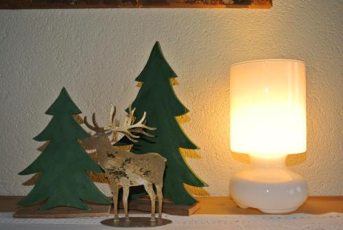 a table with a lamp and two fake christmas trees at Haus Christopherus in Klösterle am Arlberg