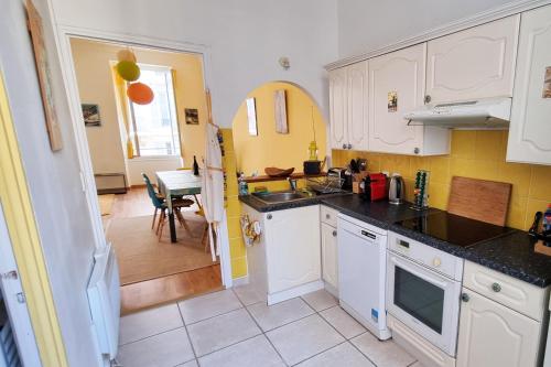 a kitchen with white cabinets and a dining room at "Le Mimosa" by EnjoyNice, in the heart of Nice with airco in Nice