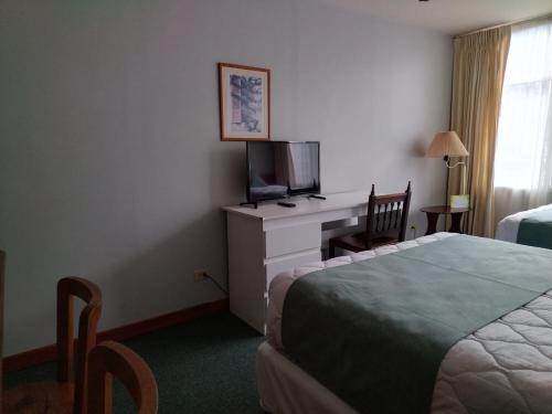 a hotel room with a bed and a desk with a television at Apartotel Tairona in San Pedro