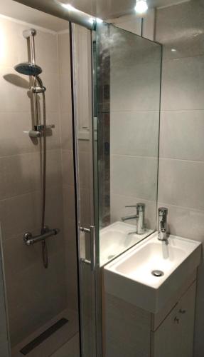 a bathroom with a sink and a shower with a mirror at Loutraki-SPA-Apartment in Loutraki