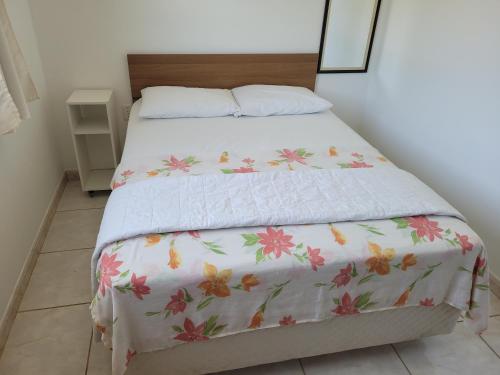 a bed with a white bedspread with flowers on it at Residencial do Angelo - Pinheira in Pinheira