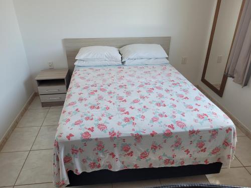a bedroom with a bed with a floral bedspread at Residencial do Angelo - Pinheira in Pinheira