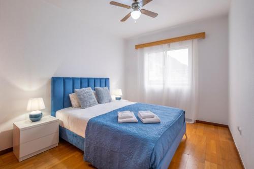 a bedroom with a blue bed with two towels on it at Sol&mar in Ponta do Sol