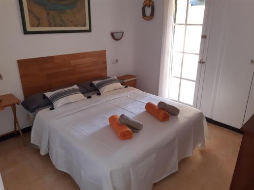 Apartamento en Calan Blanes, Ciutadella في كالا إن بلانيس: سرير أبيض مع وسادتين برتقاليتين عليه