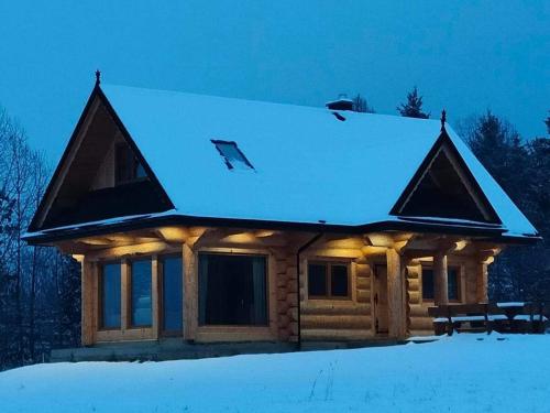 une cabane en rondins avec un toit recouvert de neige dans l'établissement beskid house, à Spytkowice