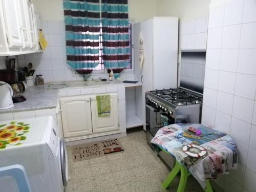 a small kitchen with a stove and a table in it at Maison à El Omrane . in Tunis