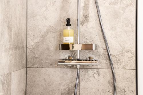 a shower with a bottle of alcohol on a shelf at Haus im WALDner in Mellau