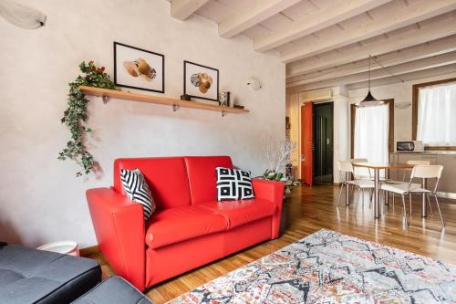 a red couch in a living room with a table at Residence dei Frutti pieno centro - Il Melograno in Padova