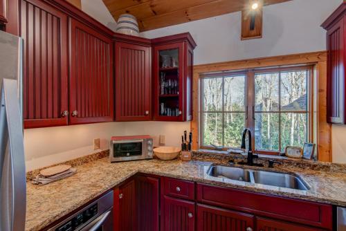 a kitchen with red cabinets and a sink and a microwave at Muir Lodge in Blowing Rock