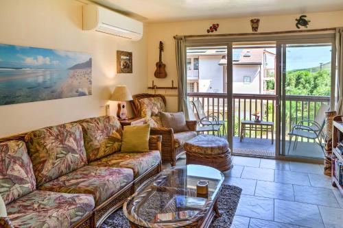 a living room with a couch and a table at Pristine Lihue Condo with Balcony Walk to Beach! in Lihue