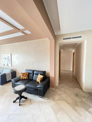 a living room with a black couch and a table at Big luxury apartment near airport in Nouaceur