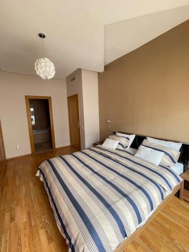 a bedroom with a large bed with a striped blanket at Big luxury apartment near airport in Nouaceur
