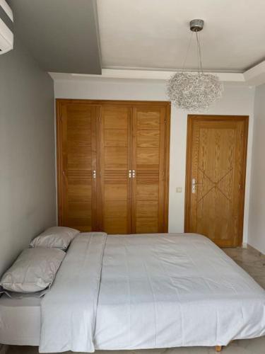 a bedroom with a large white bed and wooden cabinets at Big luxury apartment near airport in Nouaceur