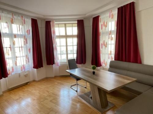 a living room with a table and red curtains at Wels Inn City Apartments in Wels