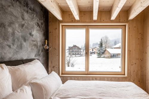 a bedroom with a bed and a large window at Haus im WALDner in Mellau