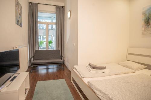 Habitación pequeña con 2 camas y silla en Innsbruck City Center Studio I 24h self-check-in, en Innsbruck