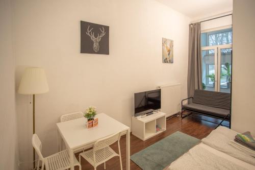 a living room with a white table and a tv at Innsbruck City Center Studio I 24h self-check-in in Innsbruck