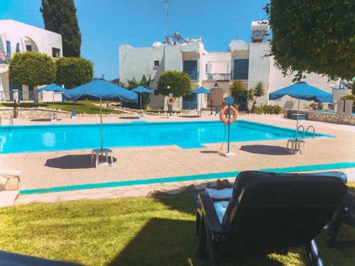 a swimming pool with a chair and blue umbrellas at Shelter next to the beach in Larnaca