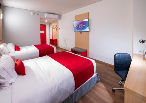 a hotel room with two beds and a chair at Ramada Encore by Wyndham Guadalajara Aeropuerto in Guadalajara