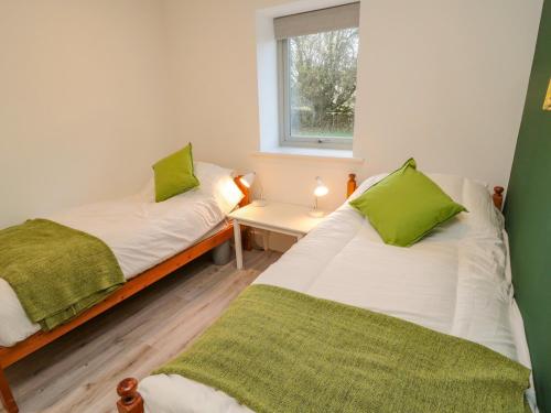2 Betten in einem kleinen Zimmer mit Fenster in der Unterkunft Clover Cottage in Newcastle upon Tyne