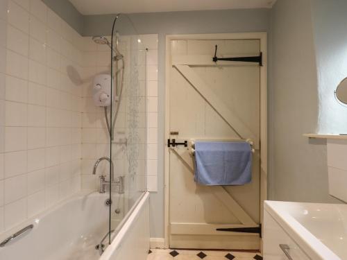 a bathroom with a shower and a tub and a sink at The Calf Pen in Colyton