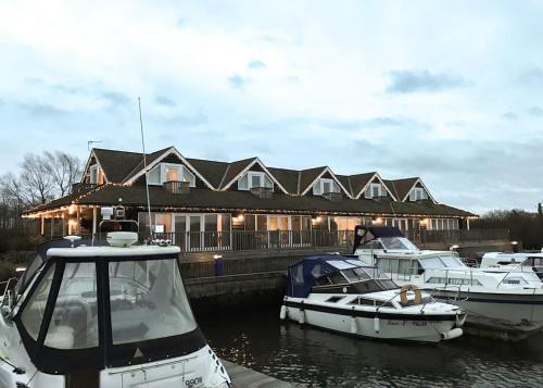 a group of boats docked in front of a house at Yare View Holiday Cottages in Brundall