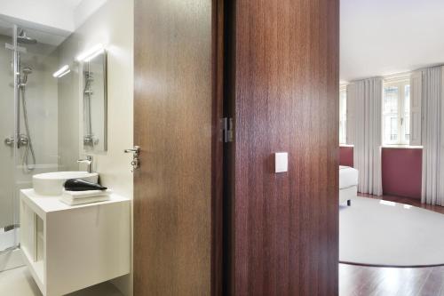 a bathroom with a wooden door and a sink at Nº150 Apartment Triplex with Suites and Terrace in Braga
