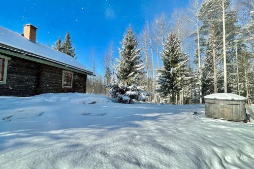 a snow covered yard next to a cabin at Log Cabin from 1820s with wood-heated sauna in Hassela
