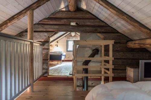 an attic room with a bed and a ladder at Log Cabin from 1820s with wood-heated sauna in Hassela