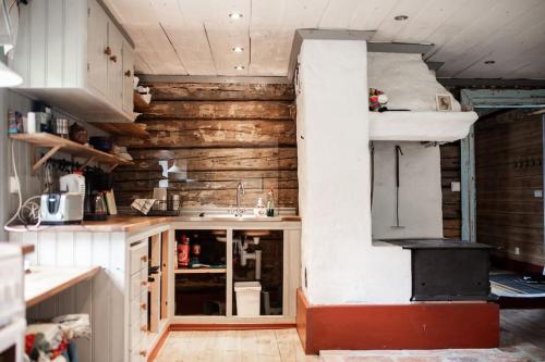 a kitchen with wooden walls and a stove at Log Cabin from 1820s with wood-heated sauna in Hassela