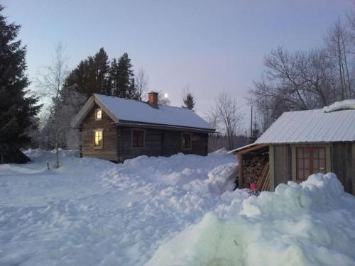 a house with a pile of snow in front of it at Log Cabin from 1820s with wood-heated sauna in Hassela