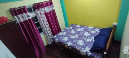 a small bedroom with a bed with purple sheets at Roofscape Homestay in Darjeeling
