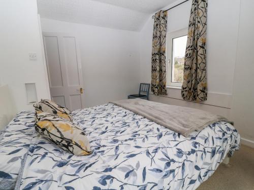 a bedroom with a bed with blue and white sheets and a window at Kestrel Cottage in Tavistock