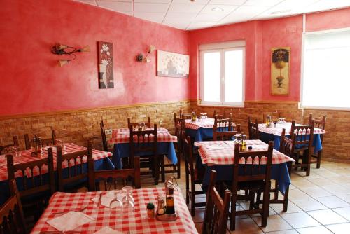 un restaurante con paredes rojas, mesas de madera y sillas en Hostal San Pedro en Coslada