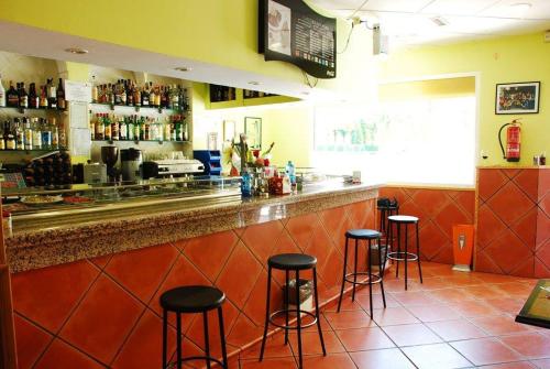 un bar con taburetes negros en un restaurante en Hostal San Pedro, en Coslada