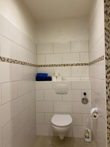 a white tiled bathroom with a toilet in it at Vermietung Petrović in Wahlrod