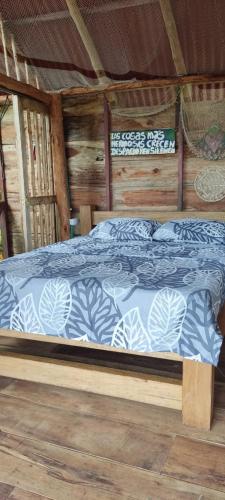 een bed met een blauw en wit dekbed in een hut bij Cabaña para pareja Tambo en coveñas in San Antero