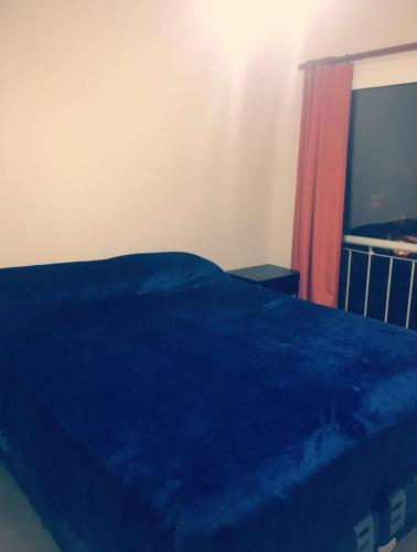 Un dormitorio con una cama azul y una ventana en Azucena Apart en Salta