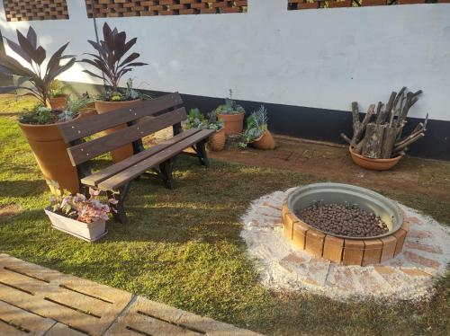 a wooden bench sitting next to a fire pit with plants at Chalé no campo in Holambra