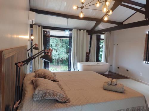 een slaapkamer met een groot bed en een bad bij Chalé no campo in Holambra
