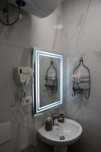 ein Badezimmer mit einem Waschbecken und einem Spiegel mit einem Vogelkäfig in der Unterkunft Blloku Studio Apartament in Tirana