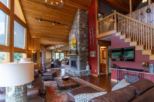 a living room with a staircase and a stone fireplace at Mountaineer Manor in Sugar Grove