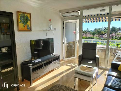 - un salon avec une télévision à écran plat et une chaise dans l'établissement Sunny Apartment Teneguia by Yumbo, à Playa del Ingles